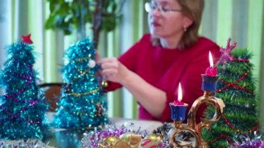 Tatil sezonu. Mutlu yaşlı bir kadın bayram için küçük bir Noel ağacı süsler. Yakın plan..
