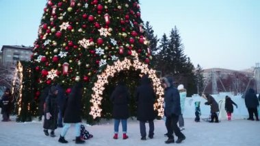 Novosibirsk, Rusya-Aralık, 12, 2021. Tatil sezonu. Vatandaşlar soğuk bir kış akşamında belediyenin Noel ağacının yanında yürürler. El ele tutuş. Sibirya.