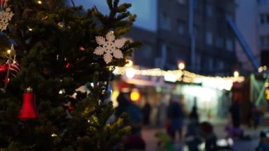 Tatil sezonu, Noel. Renkli ışıklarla süslenmiş oyuncaklarla süslenmiş bir Noel ağacı dalı ve buz kaydırağından yuvarlanan insanlar. Sibirya 'da. Bokeh.