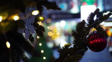 Tatil sezonu, Noel. Renkli ışıklarla süslenmiş oyuncaklarla süslenmiş bir Noel ağacı dalı ve buz kaydırağından yuvarlanan insanlar. Sibirya 'da. Bokeh.