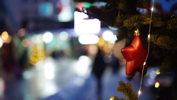ホリデーシーズン クリスマス カラーライトを背景におもちゃで装飾されたクリスマスツリーの枝やアイススライドを転がす人々 シベリアだ ぼっけ — ストック動画