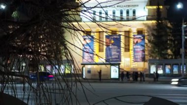 Güzel aydınlatılmış konser salonunun arka planında toplu taşıma durağı var. Elle tutulur.