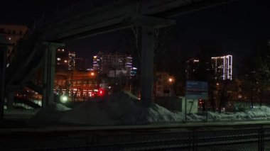 Novosibirsk, Rusya-Aralık, 12, 2021. Demiryolu üzerindeki yaya köprüsü şehrin içinden geçiyor. Kış, gece vakti.