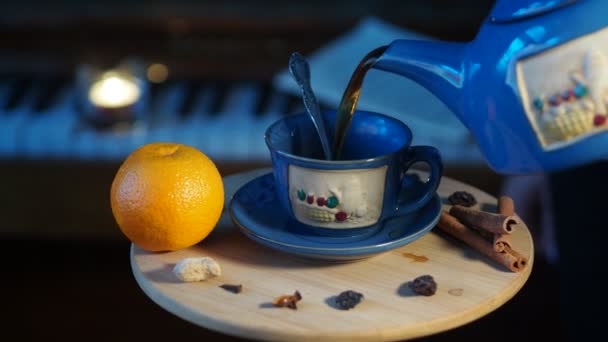 ピアノの鍵盤を背景に 女性はティーポットから小さなテーブルの上に立つカップにお茶を注ぎます パンニング クローズアップ — ストック動画