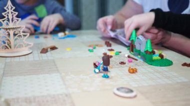 Çocuk oyunları. Yaşlı bir kadın, küçük çocukların talimatları kullanarak oyuncak evi yapmalarına yardım ediyor. Yakın plan..