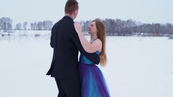一个快乐的年轻人和一个穿着舞会礼服的女人在田野里的雪地里跳华尔兹 手牵手 西伯利亚 — 图库视频影像