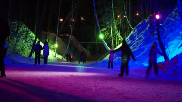 ロシアのベルズク2022年1月4日 ホリデーシーズンだ カラフルな提灯で飾られた渓谷で凍った川の氷の上の森の中で夜にスケートをする幸せな人々 シベリア — ストック動画