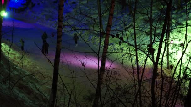 ホリデーシーズンだ カラフルな提灯で飾られた渓谷で凍った川の氷の上の森の中で夜にスケートをする幸せな人々 シベリア — ストック動画