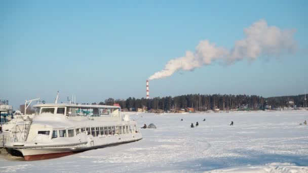 工業用煙だ 厚い煙は 船が凍る氷で覆われた川の岸に位置するガス加熱ステーションのパイプから出てきます 漁師は氷の下で釣りをしている シベリアのノヴォシビルスク — ストック動画