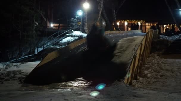 ホリデーシーズンだ 人々は 膨脹可能な円上の氷のスライドから夜に高速で移動します シベリアだ 手を握って — ストック動画