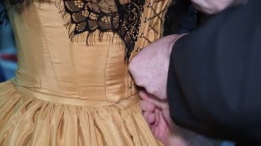 Preparation for the ball. A man helps a woman lace up a beautiful ball gown from behind. Close-up.