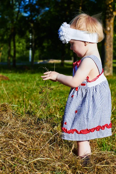 Küçük kız bir saman ile oynuyor — Stok fotoğraf