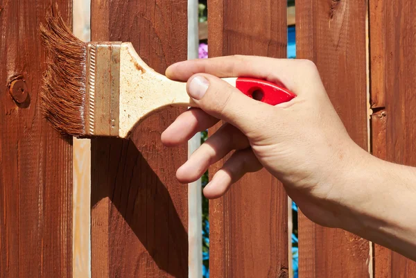 Painting wooden fence with a brown paint — Stock Photo, Image