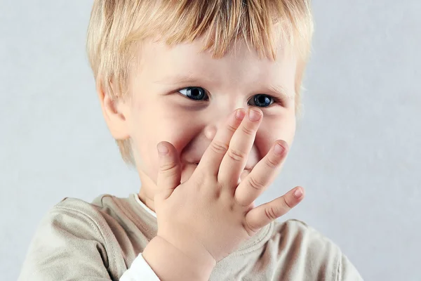 Blyg blond pojke dölja sin näsa och mun med hid hand — Stockfoto