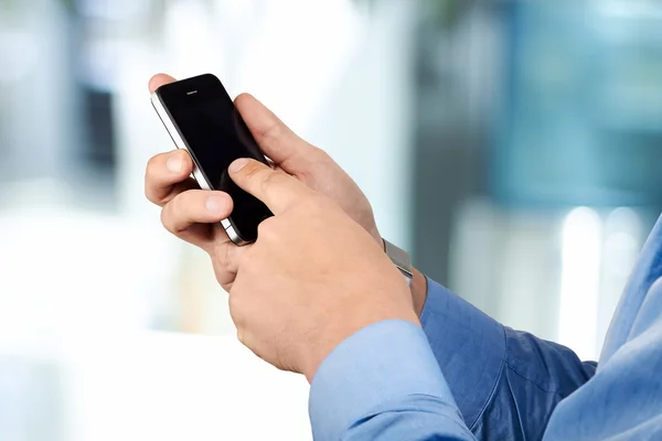 Empresario sosteniendo y utilizando el teléfono inteligente móvil — Foto de Stock