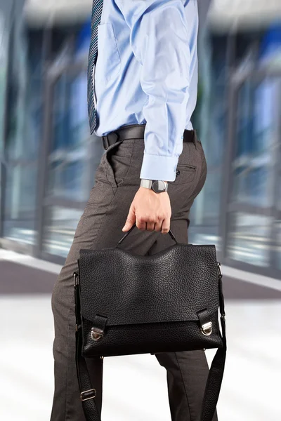 Uomo d'affari che cammina e tiene una valigetta di pelle nel suo han — Foto Stock