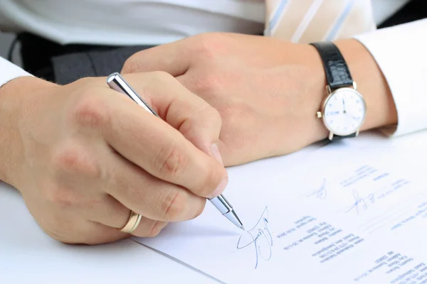 Бизнесмен сидит за рабочим столом и подписывает контракт — стоковое фото