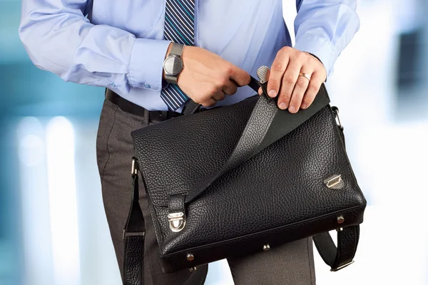 Empresario sosteniendo y abriendo un maletín de cuero — Foto de Stock
