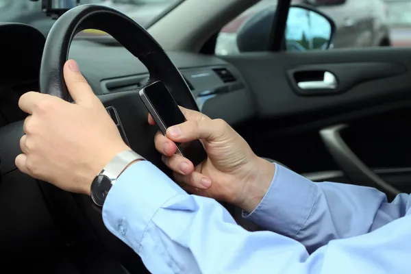 Geschäftsmann nutzt Handy während der Autofahrt — Stockfoto