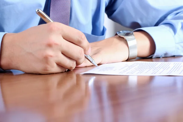 Geschäftsmann sitzt am Schreibtisch und unterschreibt einen Vertrag durch — Stockfoto