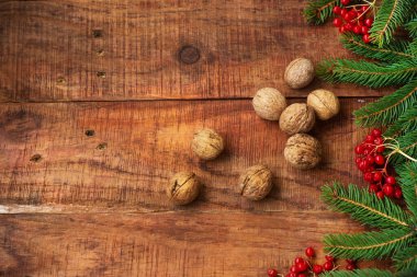 Noel arkaplanı. Ahşap arka planda ladin dalları, kırmızı böğürtlen ve ceviz. Üst Manzara. Noel ya da yeni yıl kartı. Metin için yer, kopyalama alanı, düz uzanma