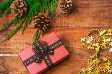 Noel arkaplanı. Ladin dalları, Yeni Yıl altın çelenkleri, kozalaklar ve ahşap bir arka planda hediye