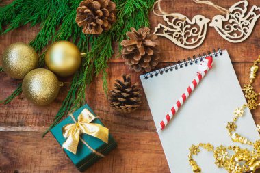 Noel arkaplanı. Ladin dalları, defter, ahşap kuş figürleri, hediye ve ahşap bir arka planda altın çelenk..
