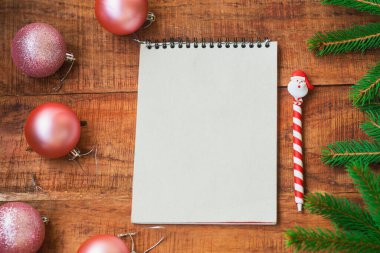 Noel arkaplanı. Ahşap arka planda pembe Noel baloları, defter ve ladin dalları. Boşluğu kopyala, çerçeve