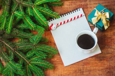 Noel arkaplanı. Spruce dalları, defter, hediye ve fincanla birlikte tahta bir arka planda kahve. Boşluğu, çerçeveyi, metin için yeri kopyala. Üst Manzara. Noel ya da yeni yıl kartı. düz yat