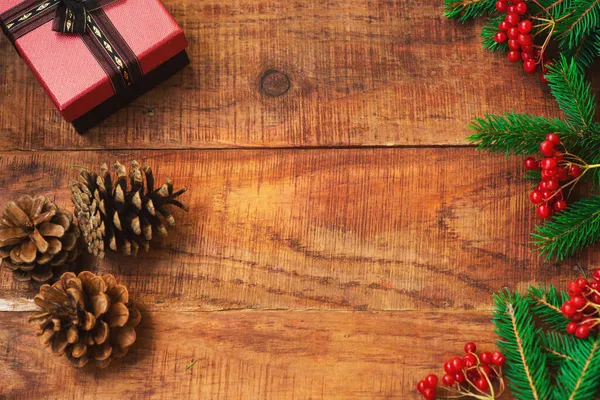 Різдвяний фон. Ялинові гілки, подарунок, гобелени, червоні ягоди на дерев'яному фоні — стокове фото