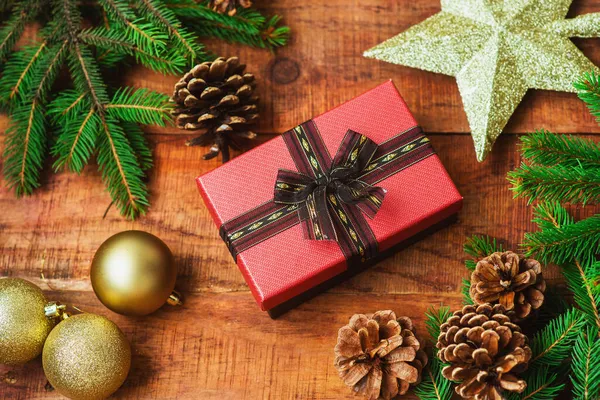 Noel arkaplanı. Spruce dalları, Noel baloları, koniler, altın yıldız ve hediye ortada tahta bir arka planda. Üst görünümü kopyala. Noel ya da yeni yıl kartı. düz yat