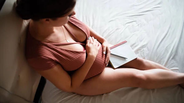 Hamile Kız Yatağa Oturur Kucağında Bir Defterle Karnını Ütüler Doğum — Stok fotoğraf