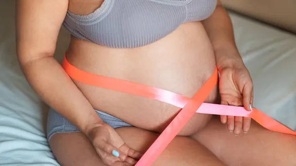 Vientre Una Chica Embarazada Con Una Cinta Rosa Alrededor Abdomen —  Fotos de Stock