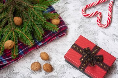 Yeni yıl veya Noel kompozisyonu ladin yeşili dallar, kırmızı ekose, ceviz, hediye ve parlak bir dokuma arka planda noel lolipopları. Düz konum, düzen, çerçeve, kopyalama alanı