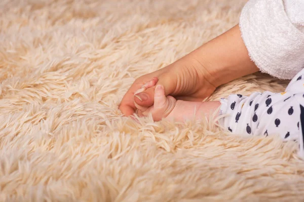Η μητέρα κρατά στα χέρια της ένα μικρό χέρι μωρού. Μικρό χέρι νεογέννητου μωρού σε απαλά χέρια της μαμάς. Το μωρό κρατάει το δάχτυλο της μητέρας — Φωτογραφία Αρχείου