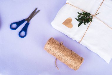 gift in eco package and green twigs from above and bundle winding and scissors on very peri background Zero waste concept. Organic material. Top view, copy space