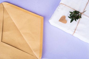 Craft paper envelope gift in eco package with green twigs from above on very pari background. Zero waste concept. Organic material. Top view, copy space