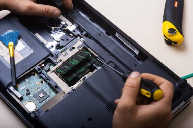 Sihirbaz dizüstü bilgisayarı restore eder. Dizüstü bilgisayarın yedek parçalarına ayrılması. Tahta, iyileşme için dizüstü bilgisayarın bir parçası. Aletleri kullanarak bilgisayar ekipmanlarının bakımı. İçerideki dizüstü bilgisayara bak