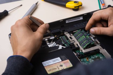 Sihirbaz dizüstü bilgisayarı restore eder. Dizüstü bilgisayarın yedek parçalarına ayrılması. Tahta, iyileşme için dizüstü bilgisayarın bir parçası. Aletleri kullanarak bilgisayar ekipmanlarının bakımı. İçerideki dizüstü bilgisayara bak