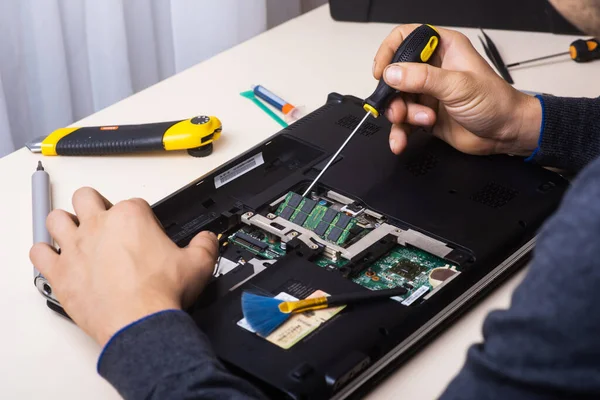 Sihirbaz dizüstü bilgisayarı restore eder. Dizüstü bilgisayarın yedek parçalarına ayrılması. Tahta, iyileşme için dizüstü bilgisayarın bir parçası. Aletleri kullanarak bilgisayar ekipmanlarının bakımı. İçerideki dizüstü bilgisayara bak