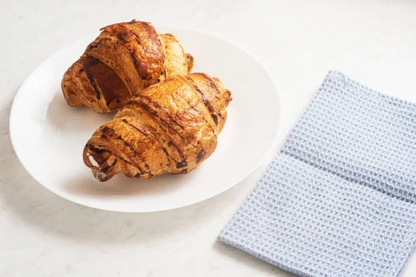 delicious, appetizing, crispy croissants and kitchen towel on plate on marble table. French pastries. Top view. Perfect breakfast. Breakfast aristocrat