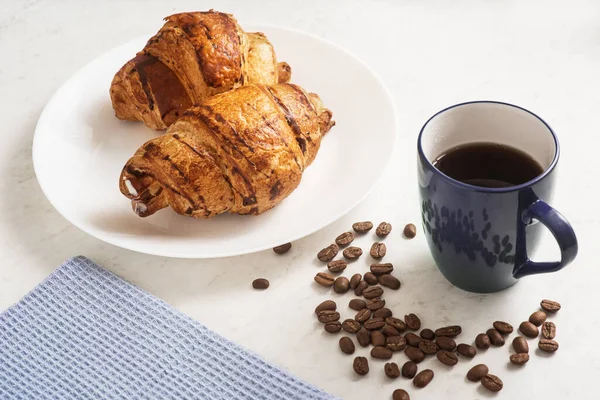 delicious, appetizing, crispy croissants, hot coffee in the blue cup and kitchen towel on plate on marble table. French pastries. Top view. Perfect breakfast. Breakfast aristocrat