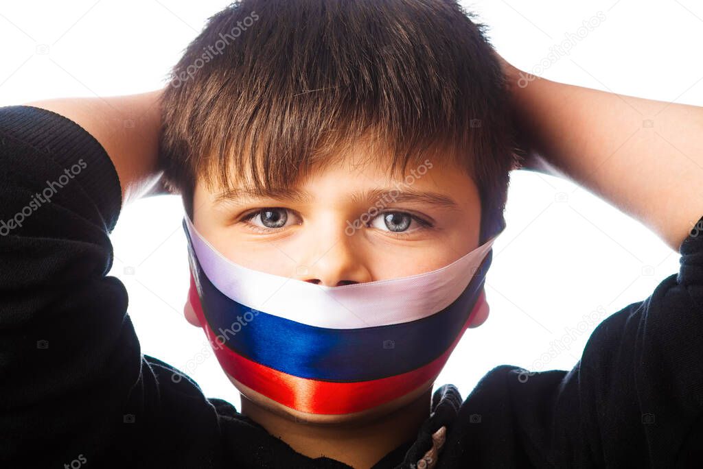 Clouse-up portrait of a boy covers his face with ribbons with flag of Russia. The escalation of Ukraine, the war. Confrontation between Ukraine and Russia