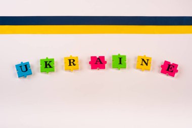 Renkli mavi-sarı kumaş kurdele ve Ukrayna 'nın beyaza izole ettiği mektup bulmacaları. Devletin sembolü. Uzayı kopyala Ulusal Flama