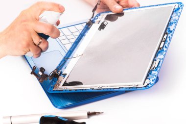 The engineer repairs blue laptop, pc, computer and the screen in the white background. laptop screen replacement nd cleaning. Installs the equipment, cpu. isolated