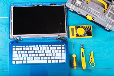 Sihirbaz dizüstü bilgisayarı aletleri ve elleri mavi ahşap masanın üzerinde tamir eder. en üstteki görünüm