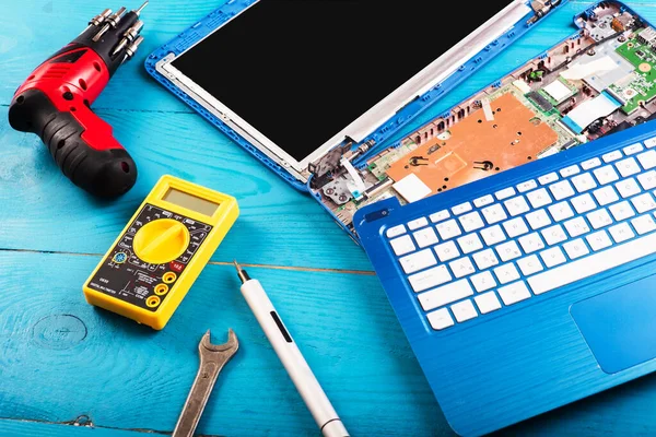 Assistente de reparação laptop com ferramentas e mãos sobre a mesa de arborização azul. vista superior — Fotografia de Stock