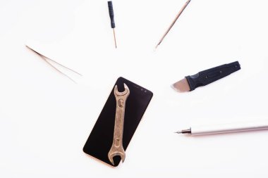 Beyaz arkaplandaki bazı bileşenleri tamir etmek veya değiştirmek için bozuk akıllı telefonu sökmenin düz bir görüntüsü vardı. Hasarlı bir cep telefonunu tamir ediyorum. İzole. Üst görünüm