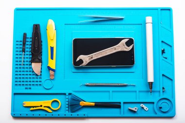 Bozuk akıllı telefonun bazı parçaları tamir etmek ya da değiştirmek için sökülmesinin düz bir görüntüsü vardı. Hasarlı bir cep telefonunu tamir ediyorum. Akıllı Telefon Tamir Aletleri. Üst görünüm