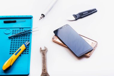 Bozuk akıllı telefonun bazı parçaları tamir etmek ya da değiştirmek için sökülmesinin düz bir görüntüsü vardı. Hasarlı bir cep telefonunu tamir ediyorum. Akıllı Telefon Tamir Aletleri. Üst görünüm